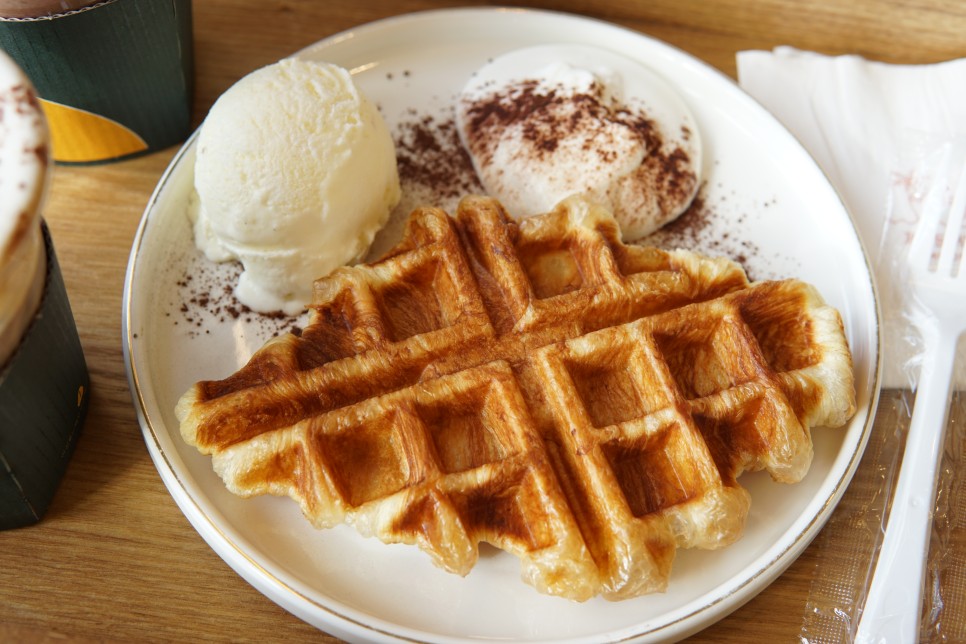 A photo of a croffle with some vanilla ice cream and whipped cream with dusted cocoa
powder.